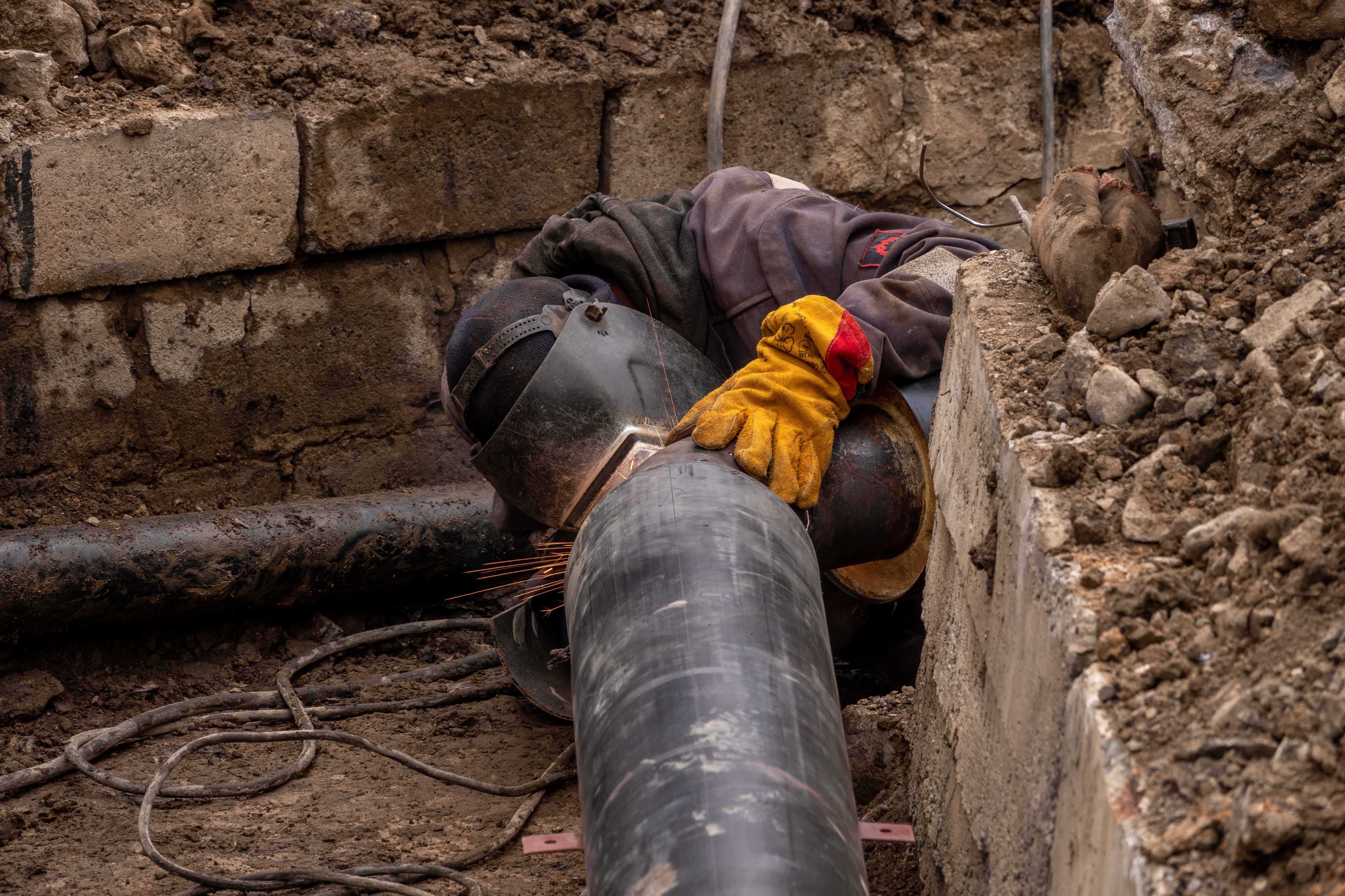 Worker repairing a large underground pipe